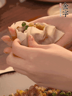 取一大勺餡料放進(jìn)餃子皮里，用大拇指按住頂部餡料，再用虎口掐出形狀。