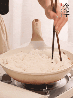 把瀝干水分的米飯均勻鋪在上面，筷子戳幾個(gè)洞，以便透氣，轉(zhuǎn)小火蓋上蓋子燜至水分收干，大概10分鐘。